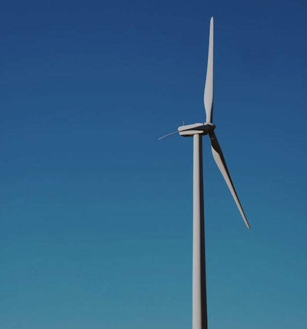 Single wind turbine with two blades against a clear blue sky.