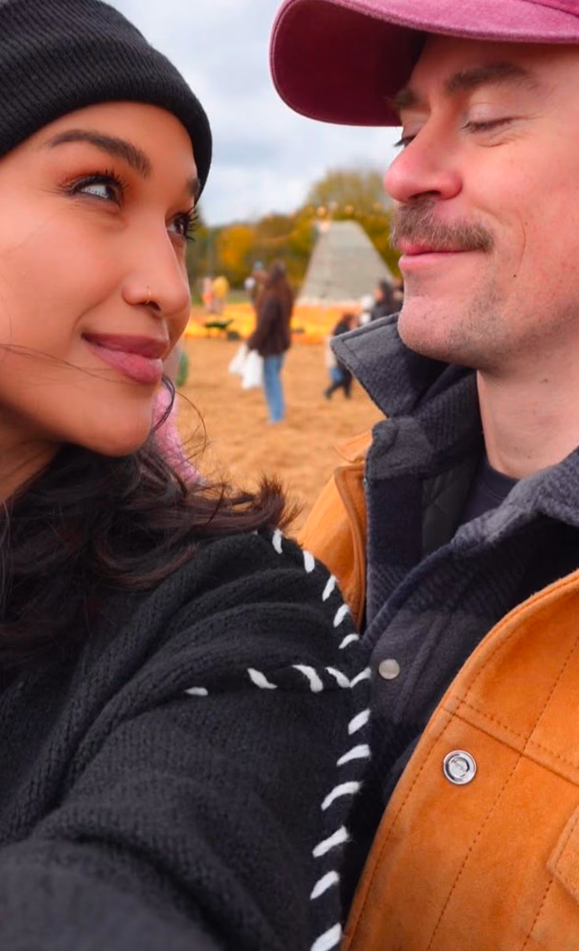 Aisha and her husband at a pumpkin patch, looking at each other