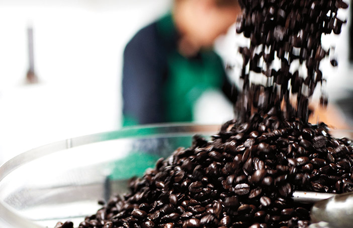 Coffee beans being poured into a roasting tray