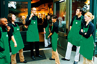 Starbucks team in green aprons outside store entrance