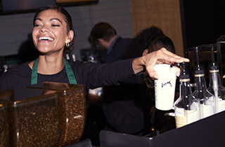 Barista laughing while preparing drinks at the counter