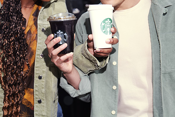 Two customers holding Starbucks hot and cold takeaway drinks