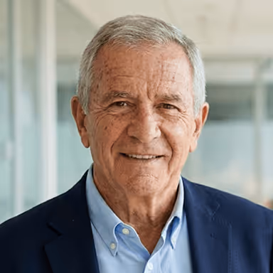 Ich weiß nicht, wer das ist.  
Älterer Mann im Business-Anzug lächelt in einem modernen Büroraum.