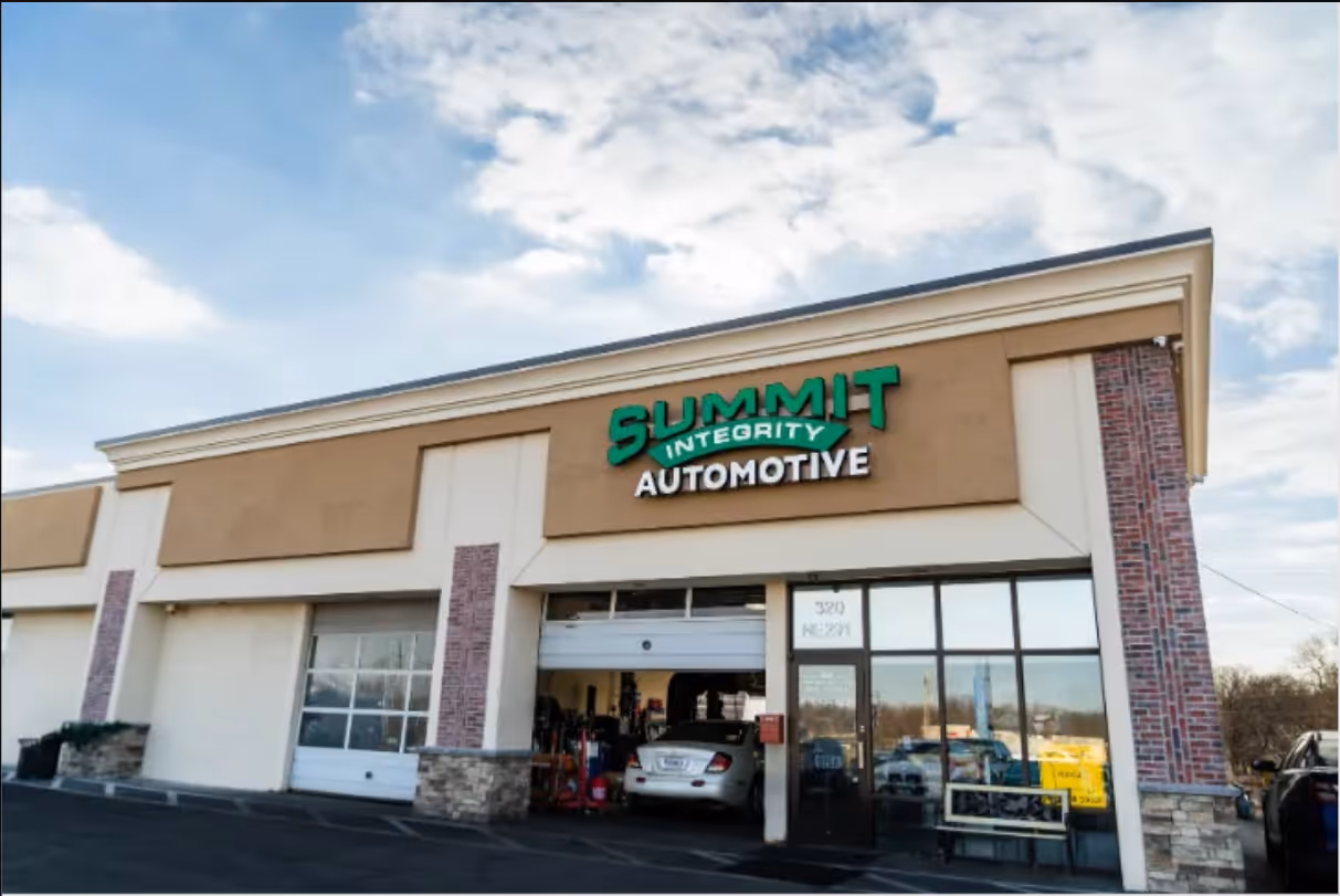 Exterior view of Summit Integrity Automotive shop with a car inside the garage and clear sky above.