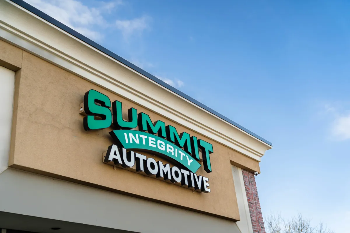 Exterior sign for Summit Integrity Automotive on a building under a blue sky.