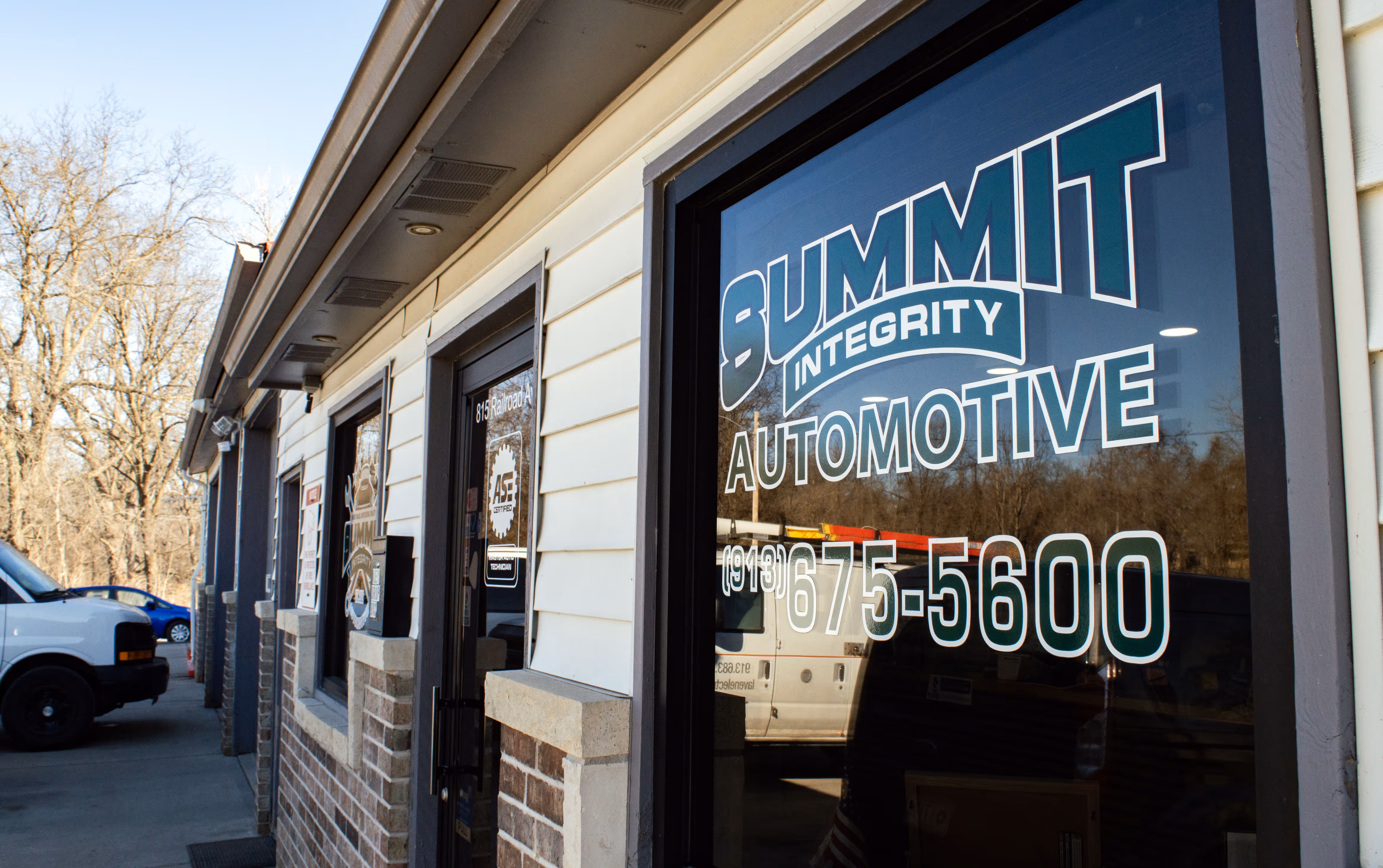 Exterior sign for Summit Integrity Automotive on a building under a blue sky.
