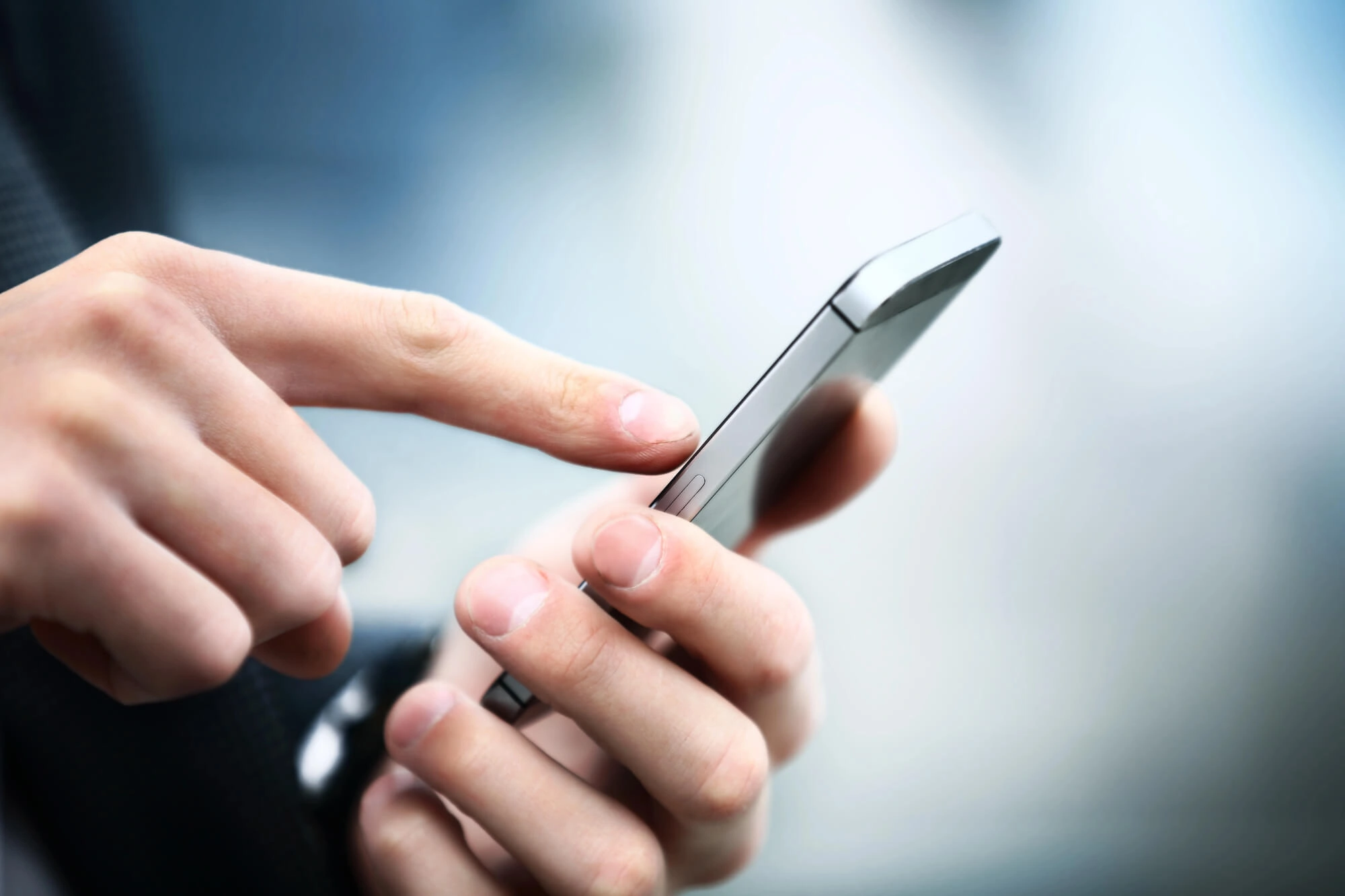 Close-up of a person holding a smartphone and touching the screen with their index finger.