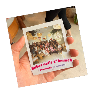 Hand holding a Polaroid photo of a group of women posing indoors with text reading 'Babes net’s 1st brunch powered by Jumper.'