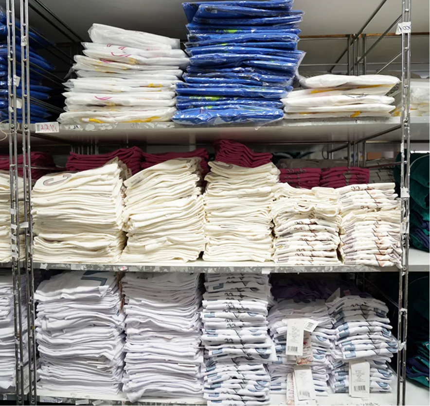 Shelves stacked with neatly folded and packaged clothing in various colors including white, blue, and maroon.