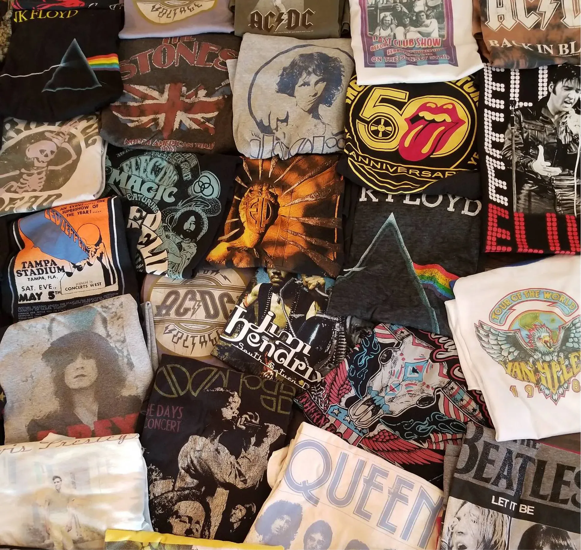 Collection of folded vintage rock band t-shirts featuring Pink Floyd, The Rolling Stones, AC/DC, The Doors, The Beatles, Queen, Jimi Hendrix, and others.