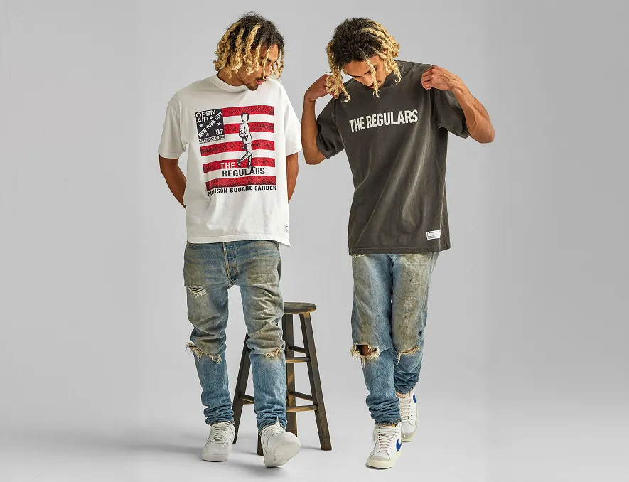 Two men with dreadlocks wear distressed jeans and printed t-shirts with The Regulars text.