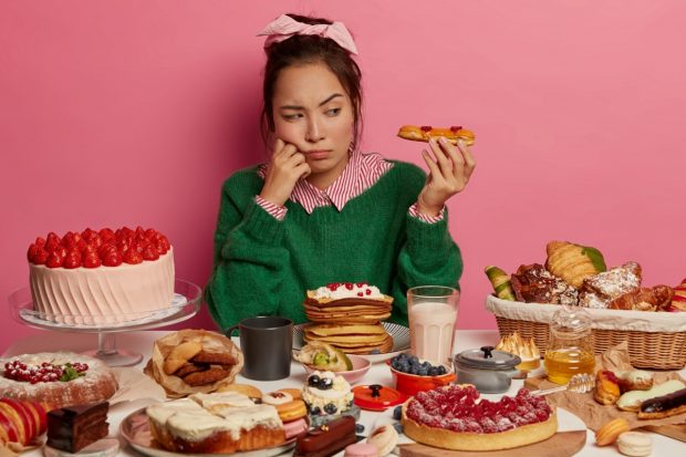 Junge Frau vor einer Fülle verschiedener Fast Food-Lebensmittel