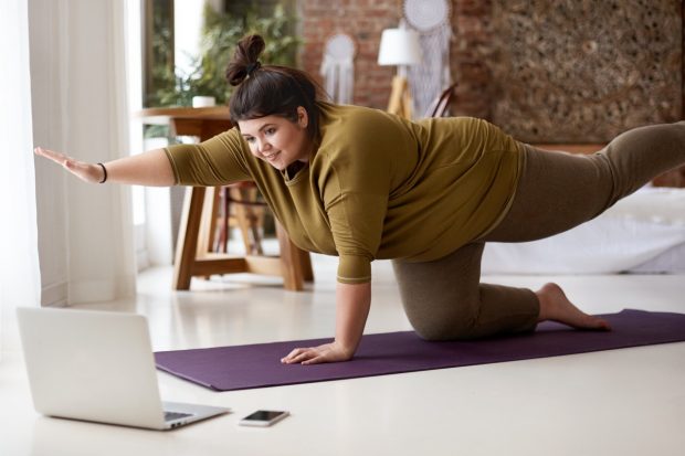 Übergewichtige junge Frau, die zu Hause Sport macht
