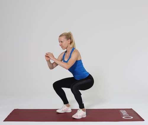 Frau macht Squat auf roter Trainingsmatte