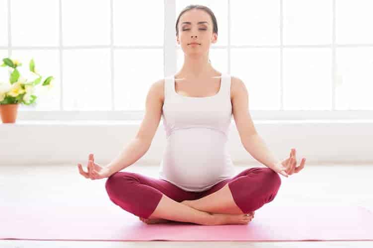 schwangere frau macht yoga schneidersitz