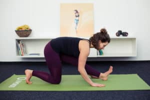 Junge Frau macht Beweglichkeitsübungen auf grüner Matte: Lunge & Runners Stretch