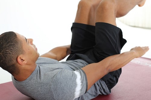Mann macht Crunches auf dunkelroter Trainingsmatte