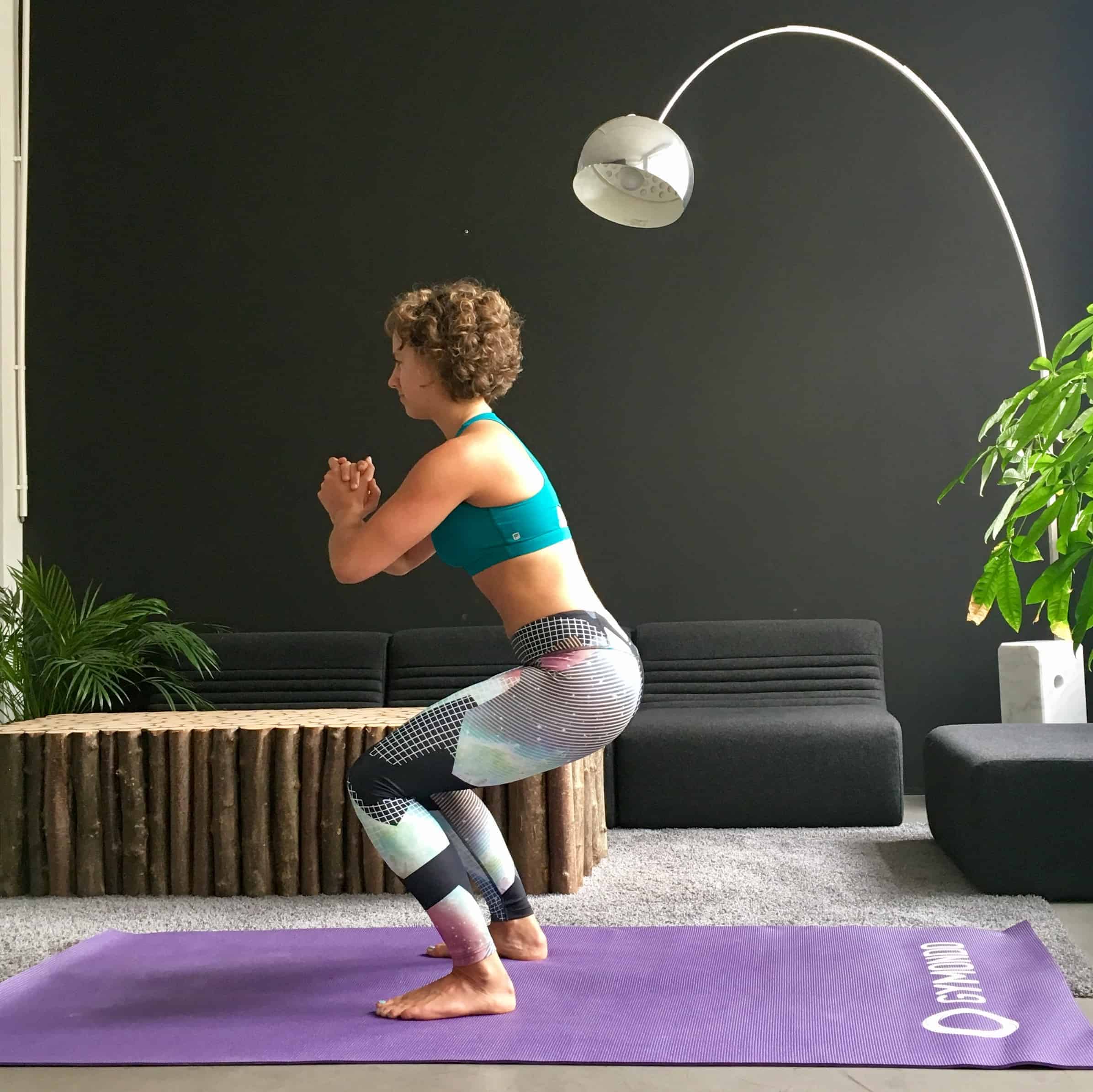 Frau macht Squats auf lila trainingsmatte