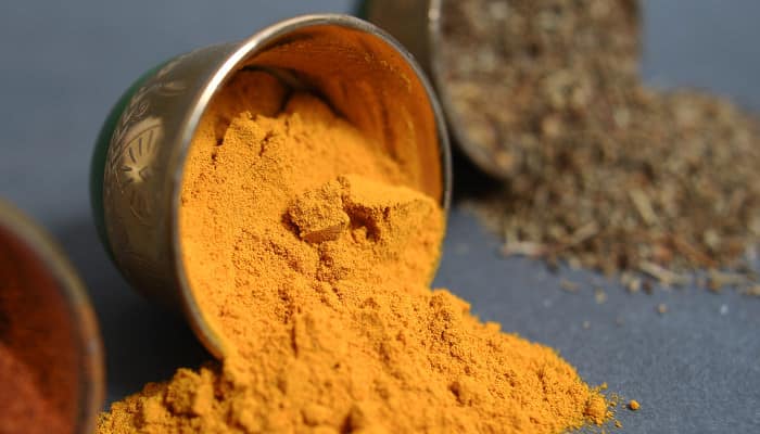 Gelbes Kurkuma-Pulver in umgekippter metallener Schüssel