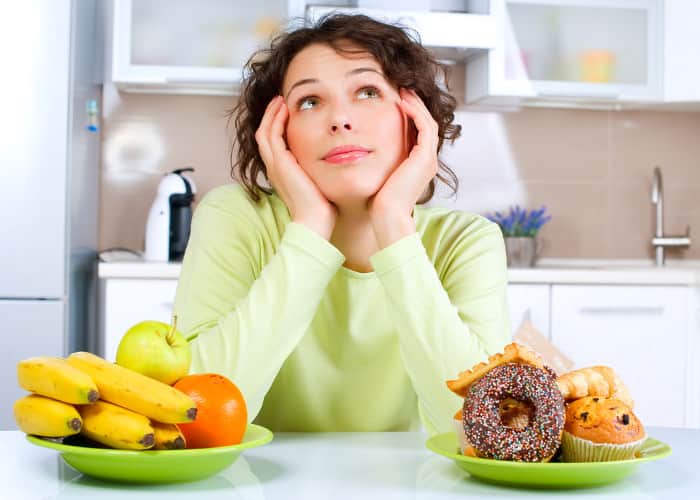 Frau, die zwischen gesundem und ungesundem Essen hin- und hergerissen ist