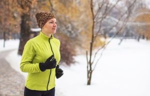 Frau mit Mütze und Handschuhen joggt im Winter.