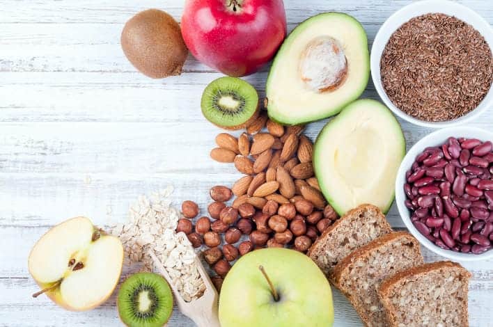 Ein Tisch mit Ballaststoffreichen Lebensmitteln wie Äpfeln, Vollkornprodukte, Bohnen