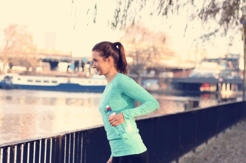 Julia führt die Übung „Trizeps Extensions“ mit Wasserflaschen aus.