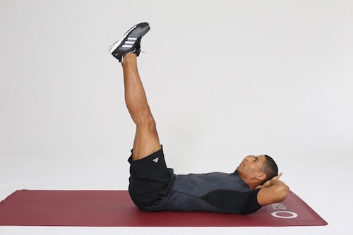 Mann macht Reverse Crunches auf dunkelroter Trainingsmatte