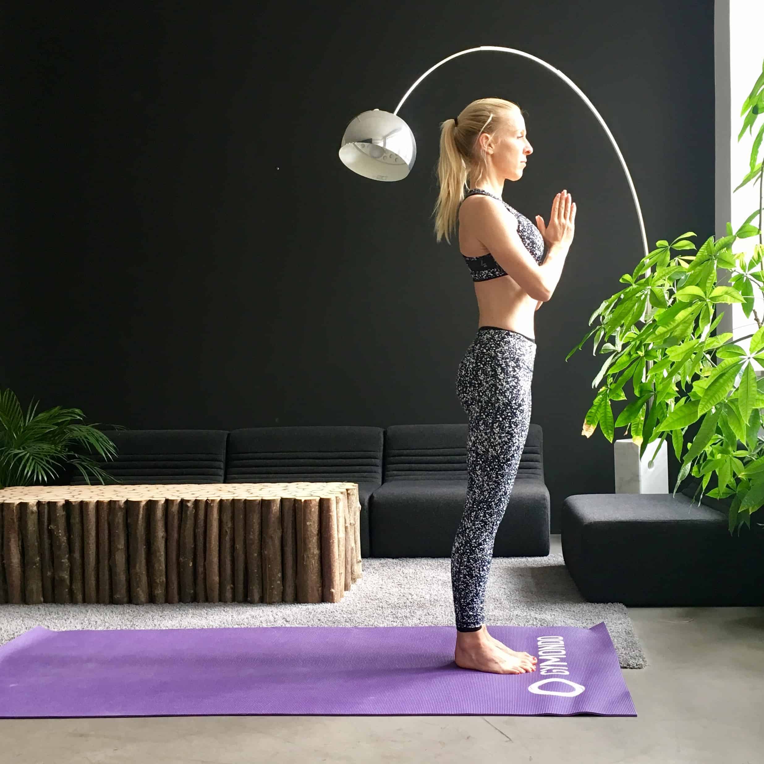 Frau macht Yoga Sonnengruß Berg auf lila Trainingsmatte