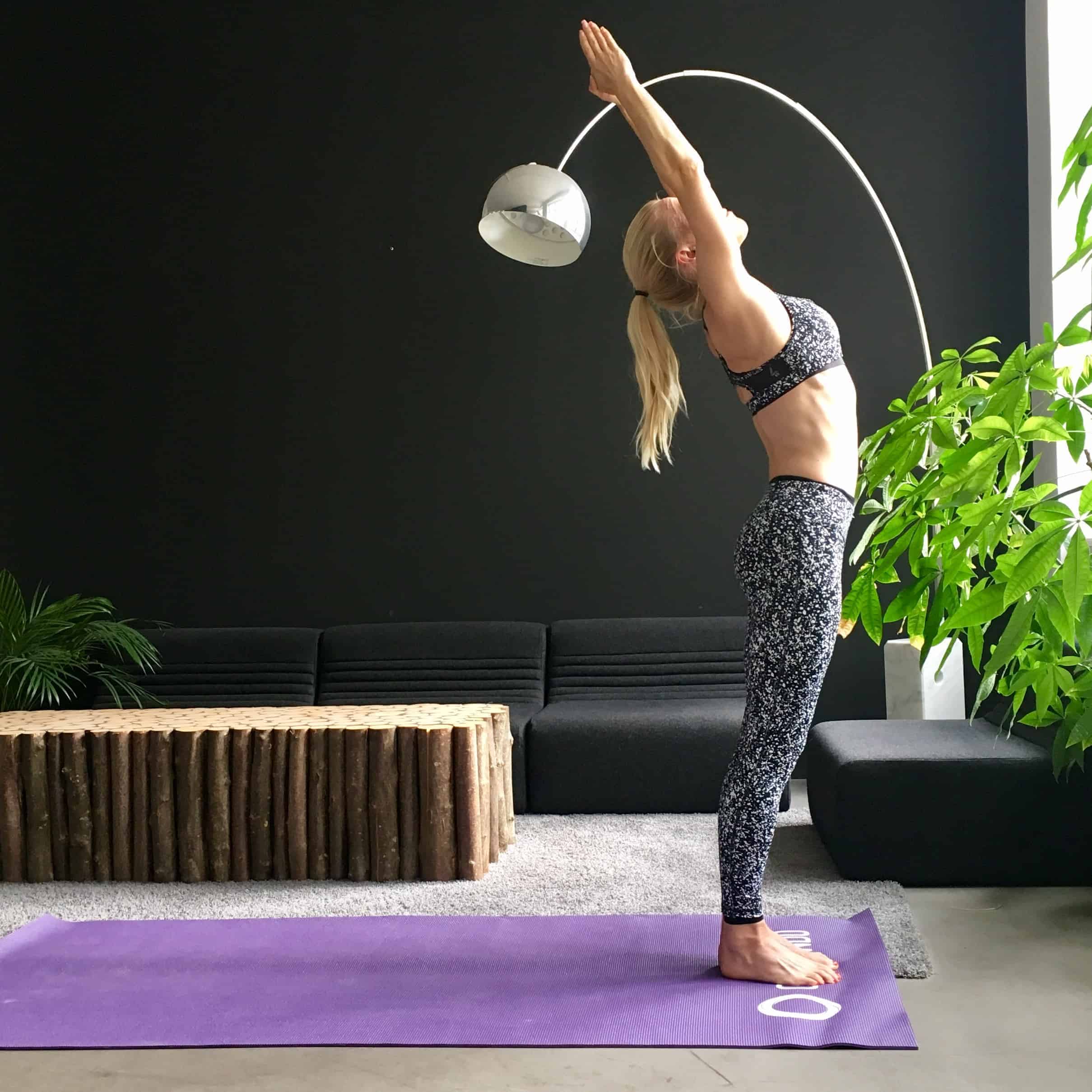 Frau macht Yoga Sonnengruß gestreckter Berg auf lila Trainingsmatte