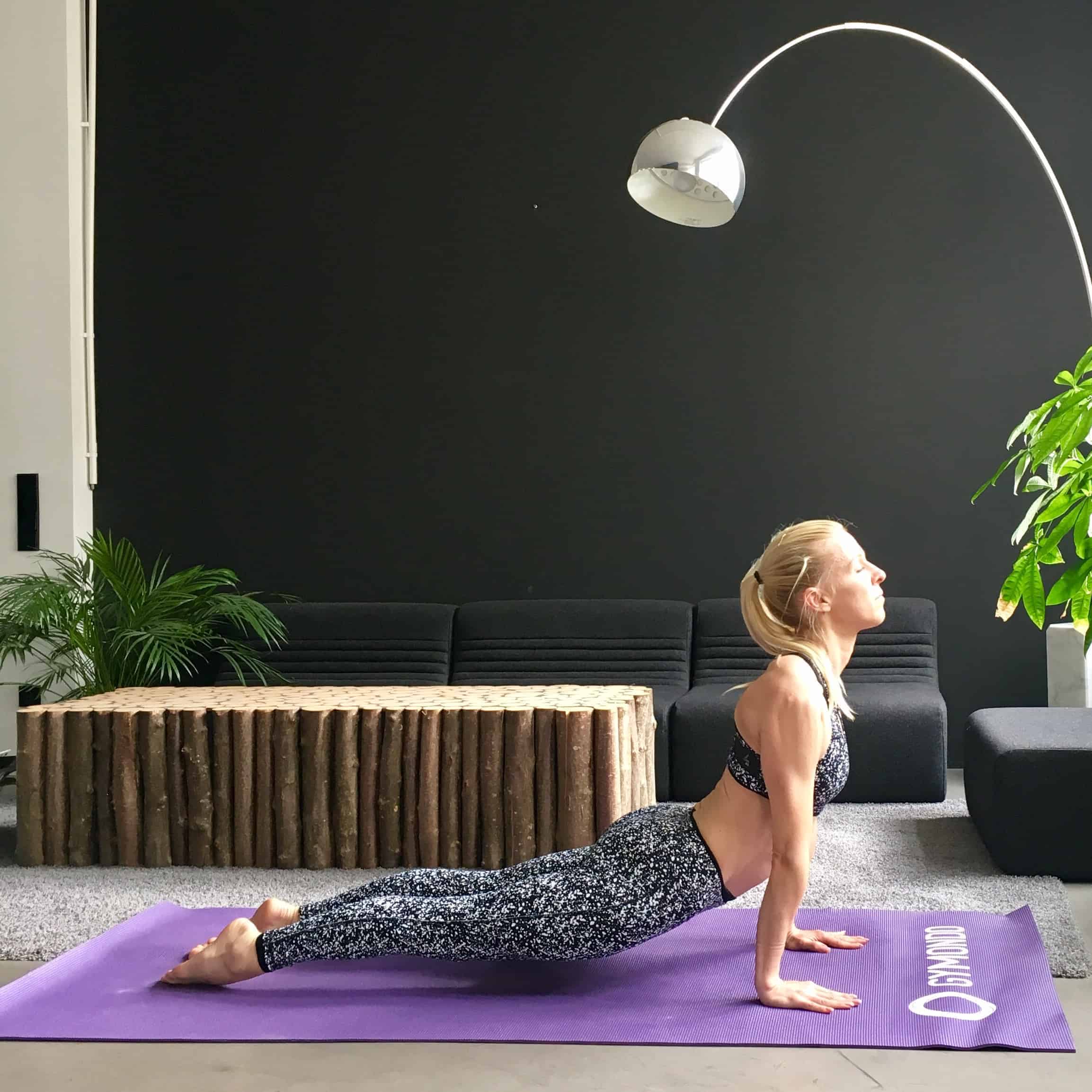 Frau macht Yoga Sonnengruß up dog auf lila trainingsmatte