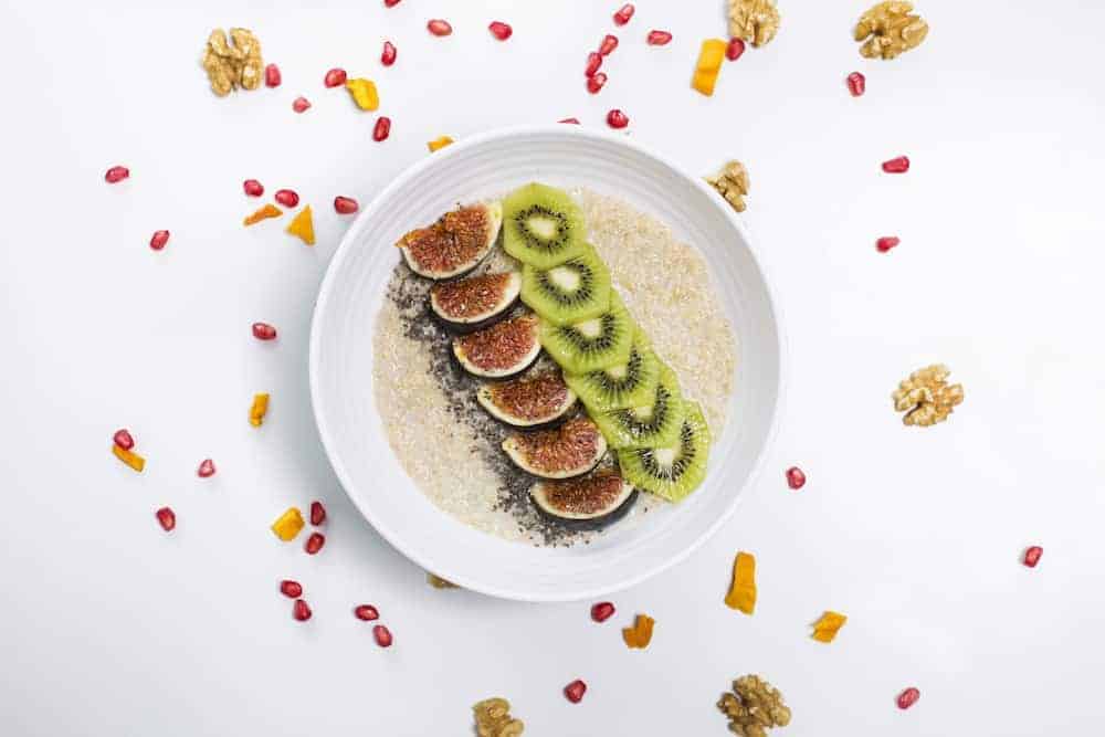 weiße Schale mit Quinoa Frühstücksbrei garniert mit Kiwi und Feigen
