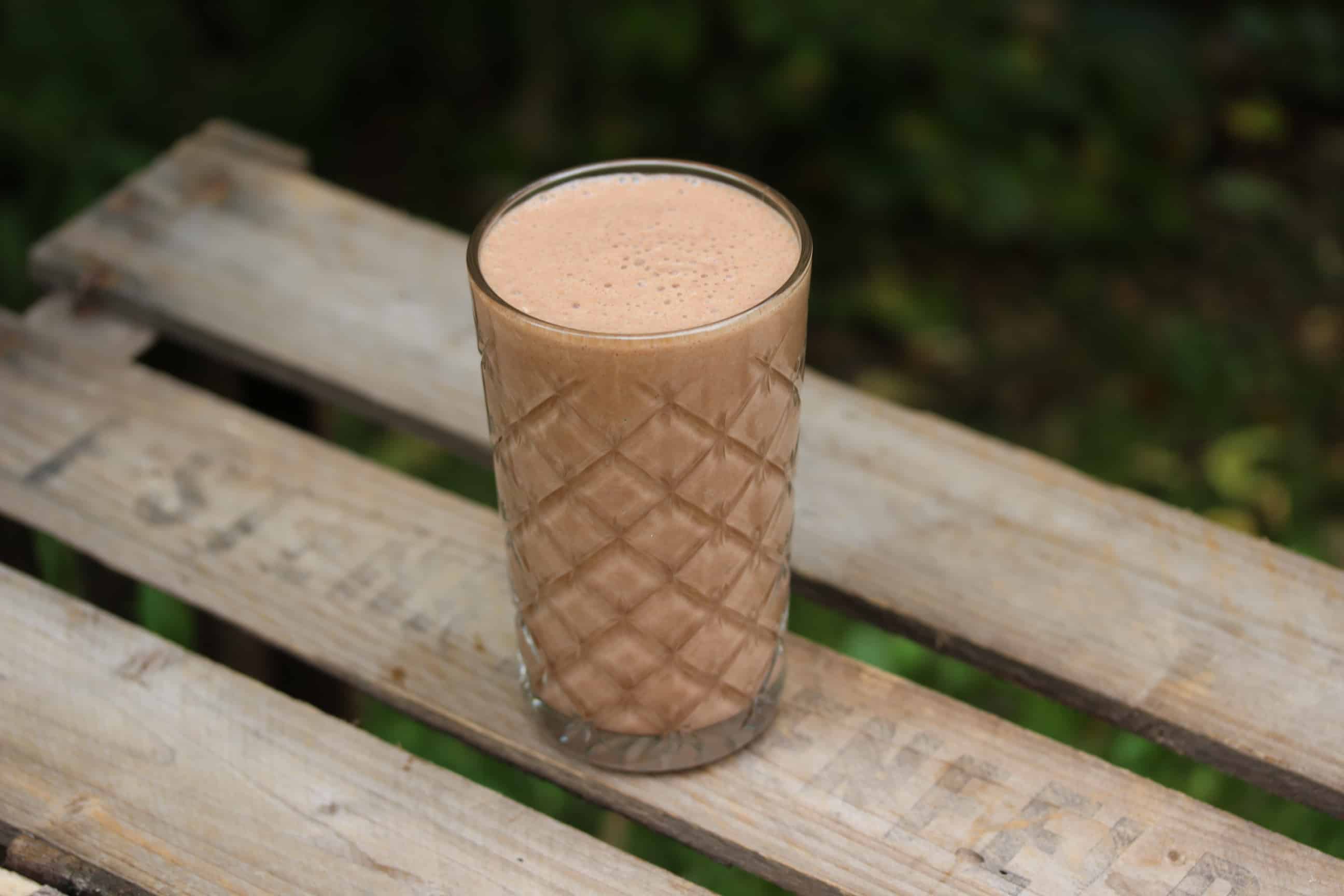 SuperGoodFood Banana-Coconut-Raw Cacao Proteinshake in Glas auf Holztisch