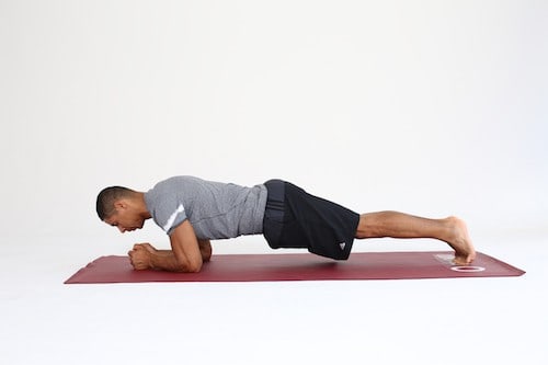 Mann macht Plank Shift auf dunkelroter Trainingsmatte