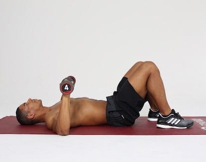 Mann macht Chest Press auf dunkelroter Trainingsmatte