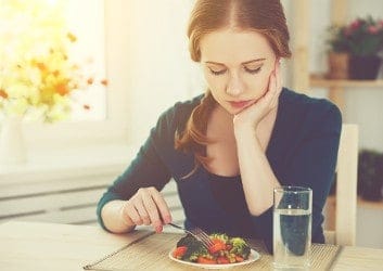 Frau stochert lustlos mit Gabel in ihrem Salat