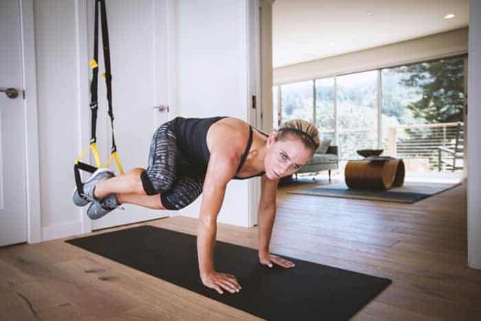Sportlerin mit dem TRX im Wohnzimmer