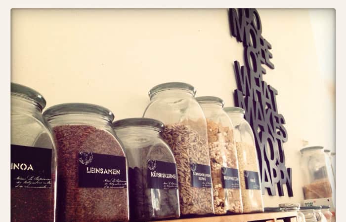 Samen, Körner und Nüsse in Glassbehältern auf einem Holzregal