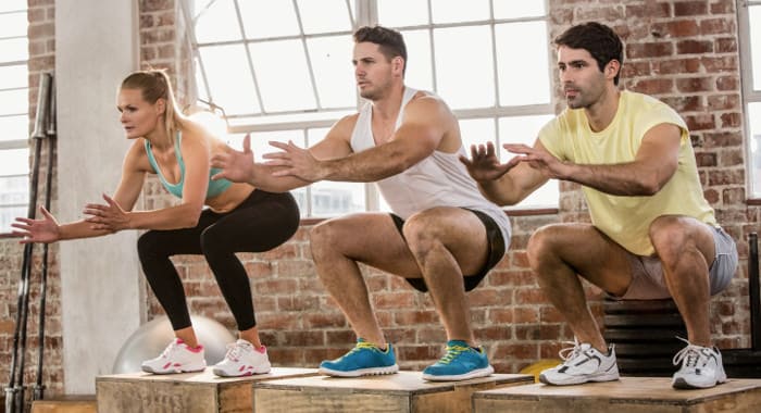 3 Sportler machen Jumping Squats