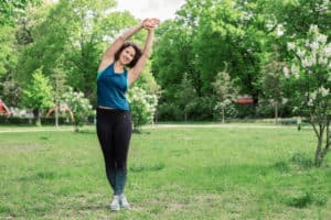 Junge Frau auf einer Raststätte macht Übung Lat Stretch