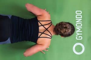Junge Frau auf einer hellgrünen Trainingsmatte macht Liegestützen