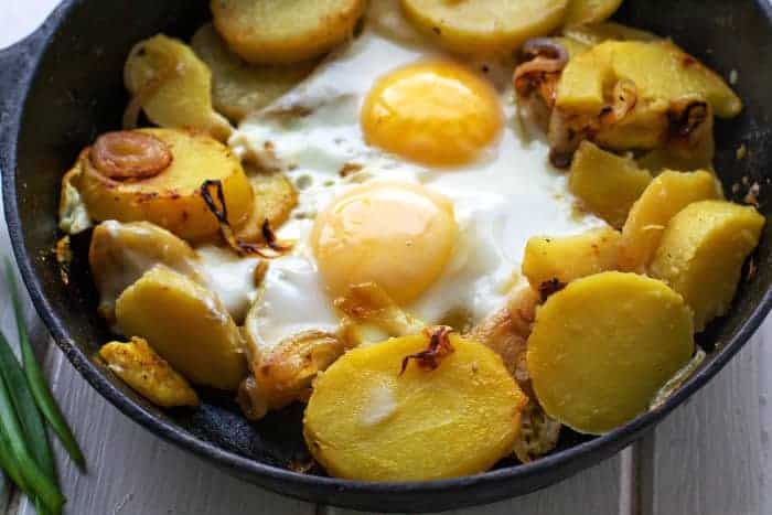 Bratkartoffeln mit Spiegeleiern in der Pfanne