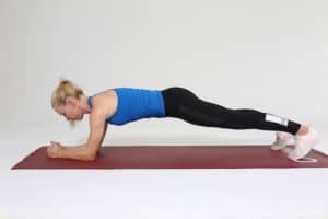 Frau macht Plank auf roter Trainingsmatte