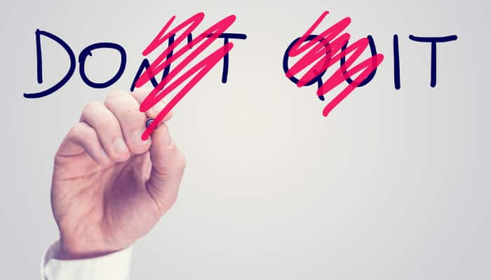 Männerhand, die aus dem an eine Glasscheibe geschriebenen Schriftzug 'Don't Quit' die Worte 'Do it' herausstreicht