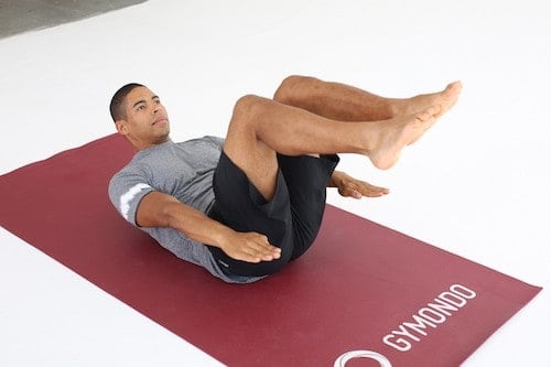 Mann macht Crunches auf dunkelroter Trainingsmatte