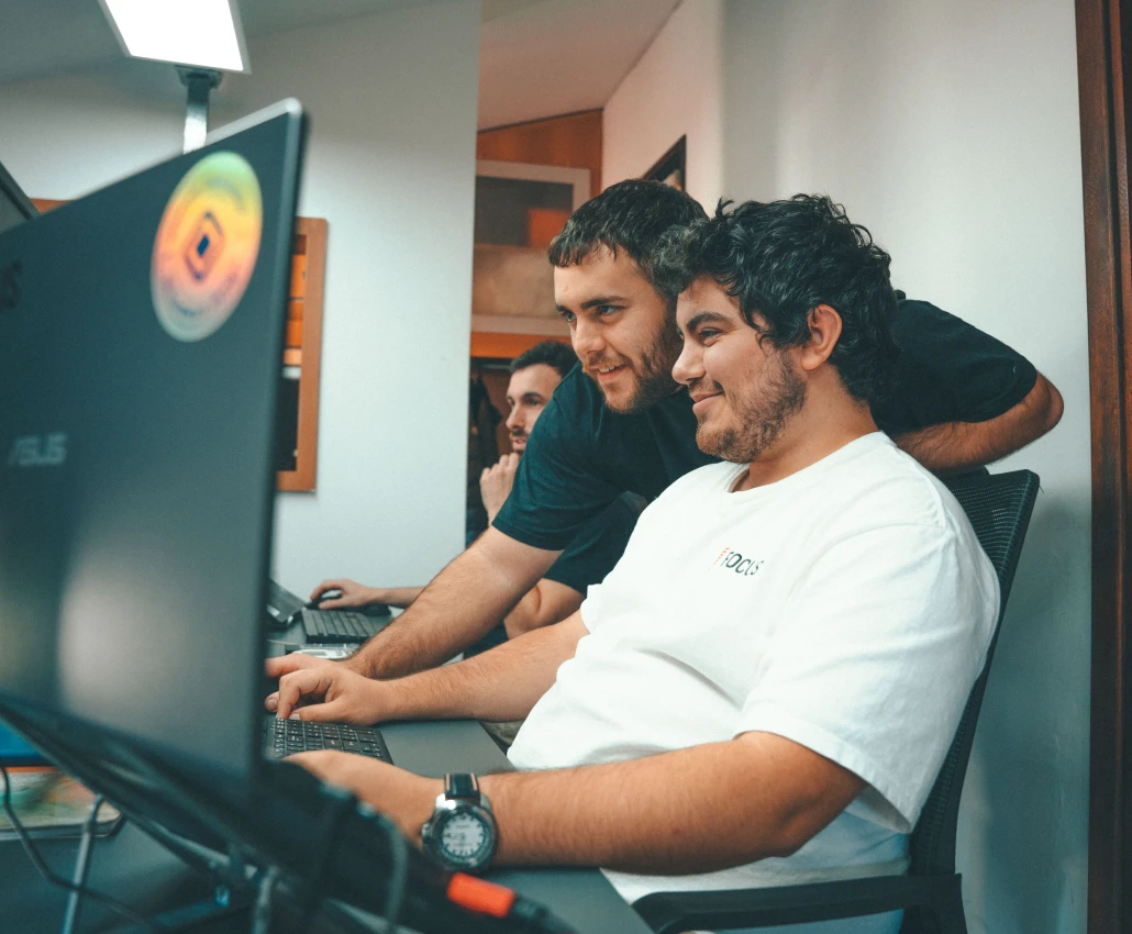 Three men working together at desks with computers in an office.