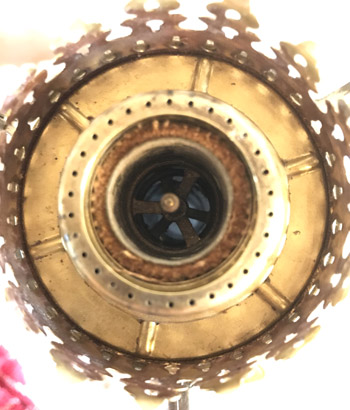 Close-up top view of a brass-colored vintage lantern or lamp with a perforated metal outer ring.