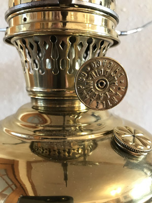 Close-up of a shiny brass vintage lantern with focus on the control knob and vent holes.