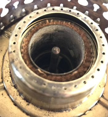 Close-up of a metallic circular component with inner cylindrical cavity and rust around its edges.