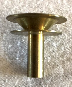 Brass candle holder with a wide rim and short cylindrical base on a textured surface.